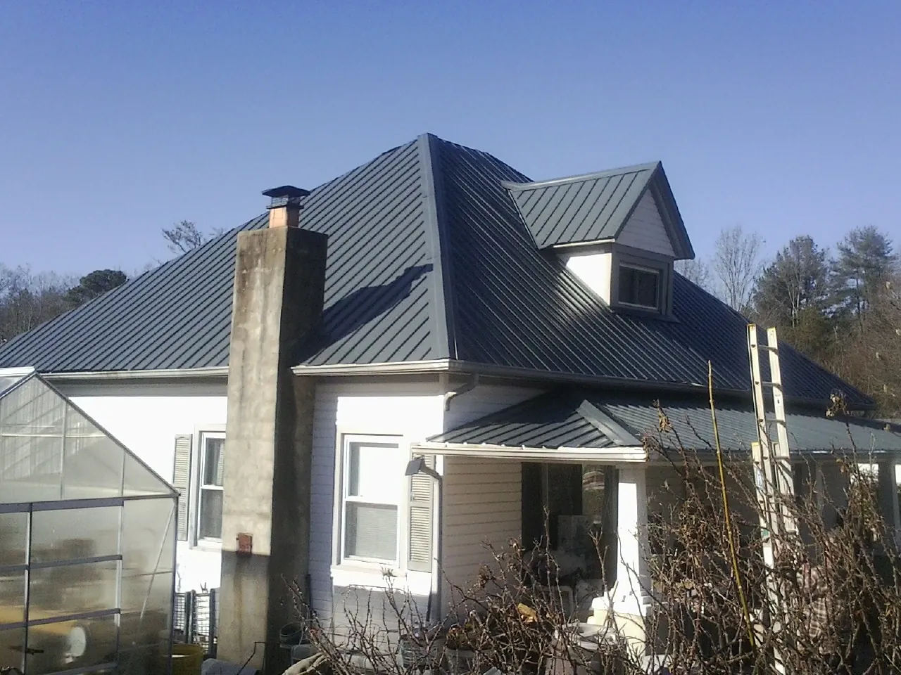 Dark blue standing seam metal roof on a white farmhouse with dormer — Slate & Tile Roof Repair by Roofing Brothers in Greenbush