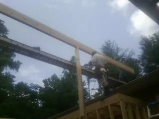 Carpenter setting a ridge beam over a new addition frame — Ice Dam Removal by Roofing Brothers in Greenbush