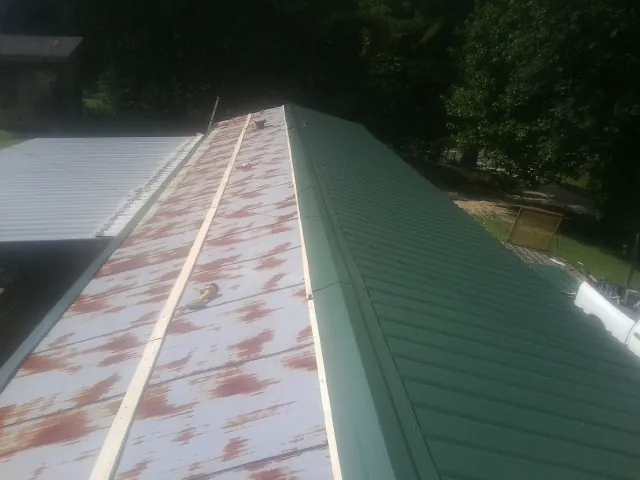 Old rusted panels beside newly installed green metal roofing — Wind Damage Roof Repair by Roofing Brothers in Greenbush
