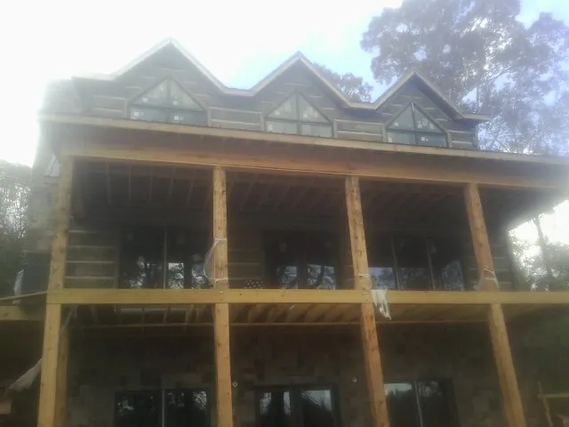 Dormers and porch framing on a large log home under construction — Roof Coating work by our crew in Greenbush
