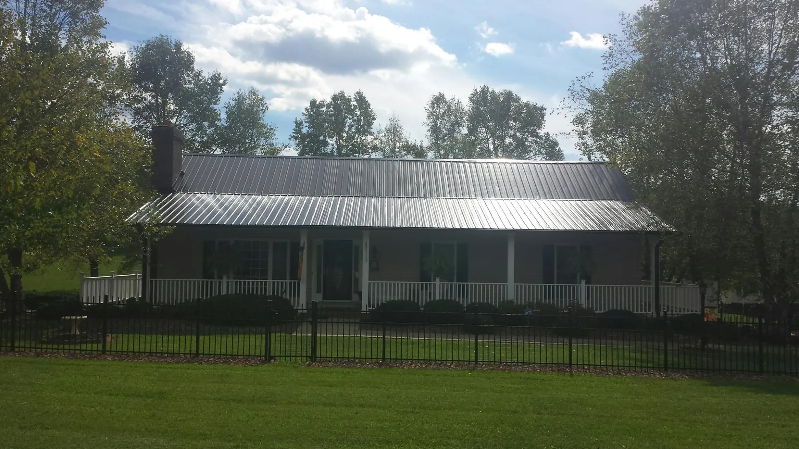 Gray metal roof on a brick ranch with a full width front porch — Gutter Guard Installation work by our crew in Greenbush