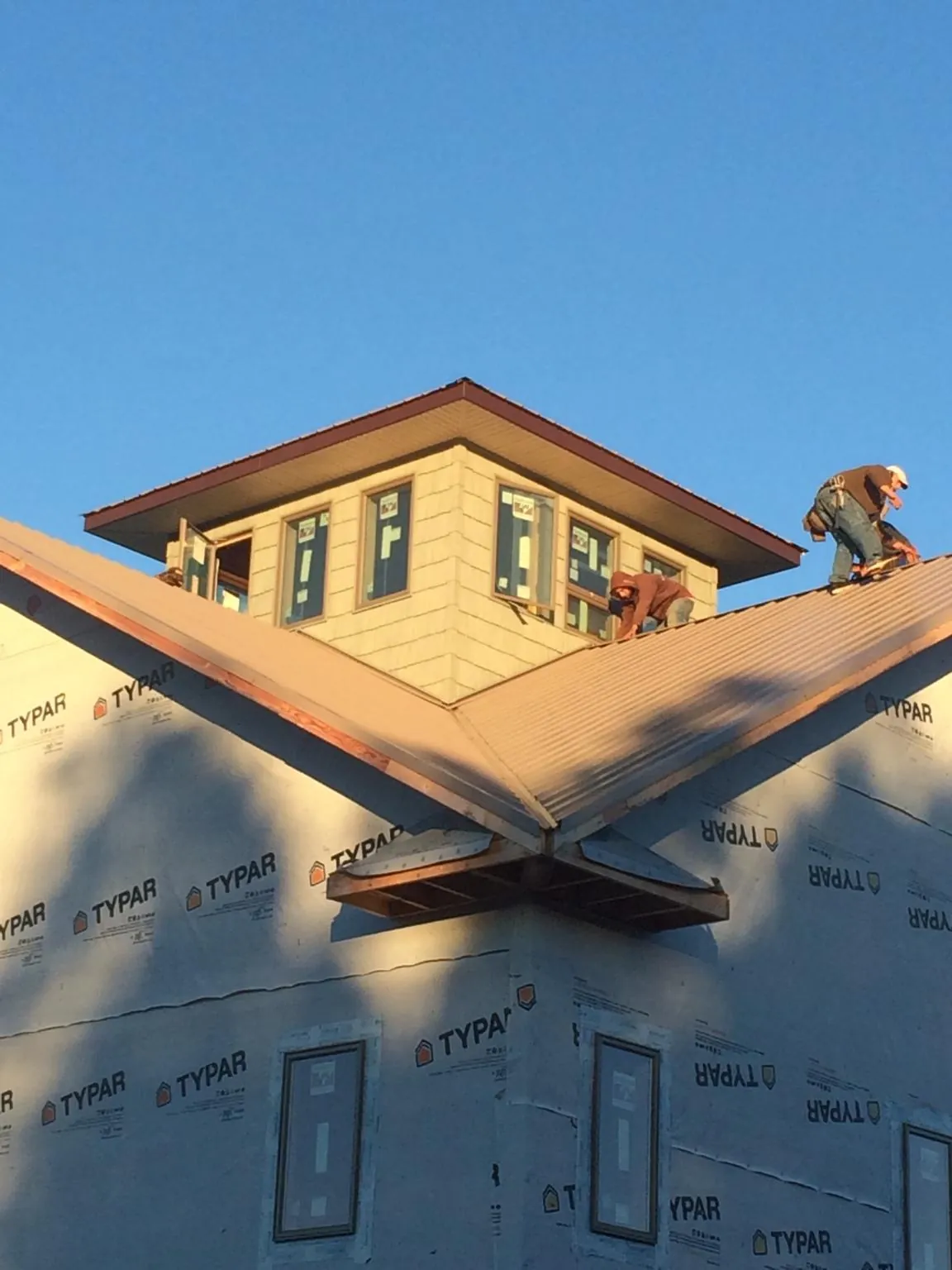 Roofers working around a rooftop cupola on a new metal roof at sunset — Roof Waterproofing in Greenbush by Roofing Brothers